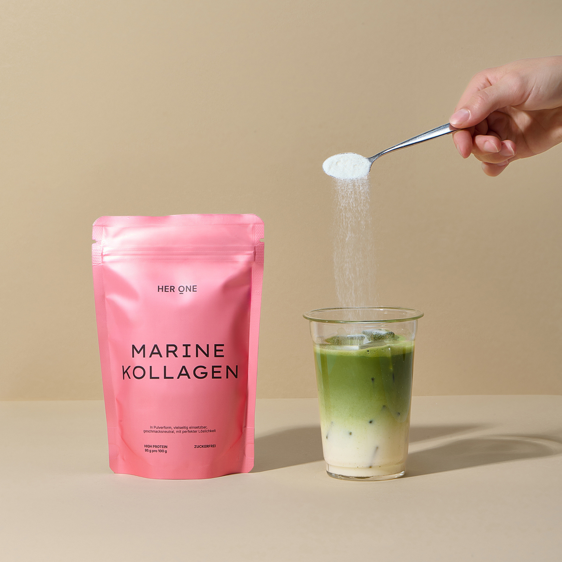 HER ONE MARINE COLLAGEN sachet next to glass with green matcha drink, powder is stirred in.