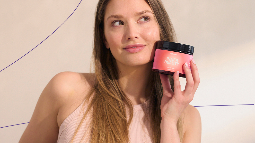 Woman in a sleeveless top holds a pink product called "Inner Beauty" and looks to the side.