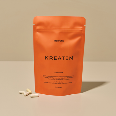 Orange pack labeled "Creatine" and white capsules lying next to it on a table.