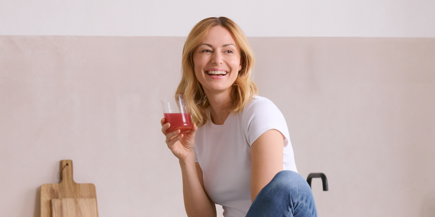 Fraulächeln undhältenGlas mitINNERBEAUTYinHand