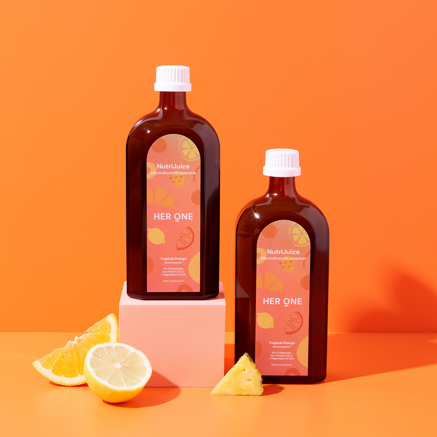 Deux bouteilles brunes avec des étiquettes orange se dressent sur un fond orange, entourées de rondelles de citron.