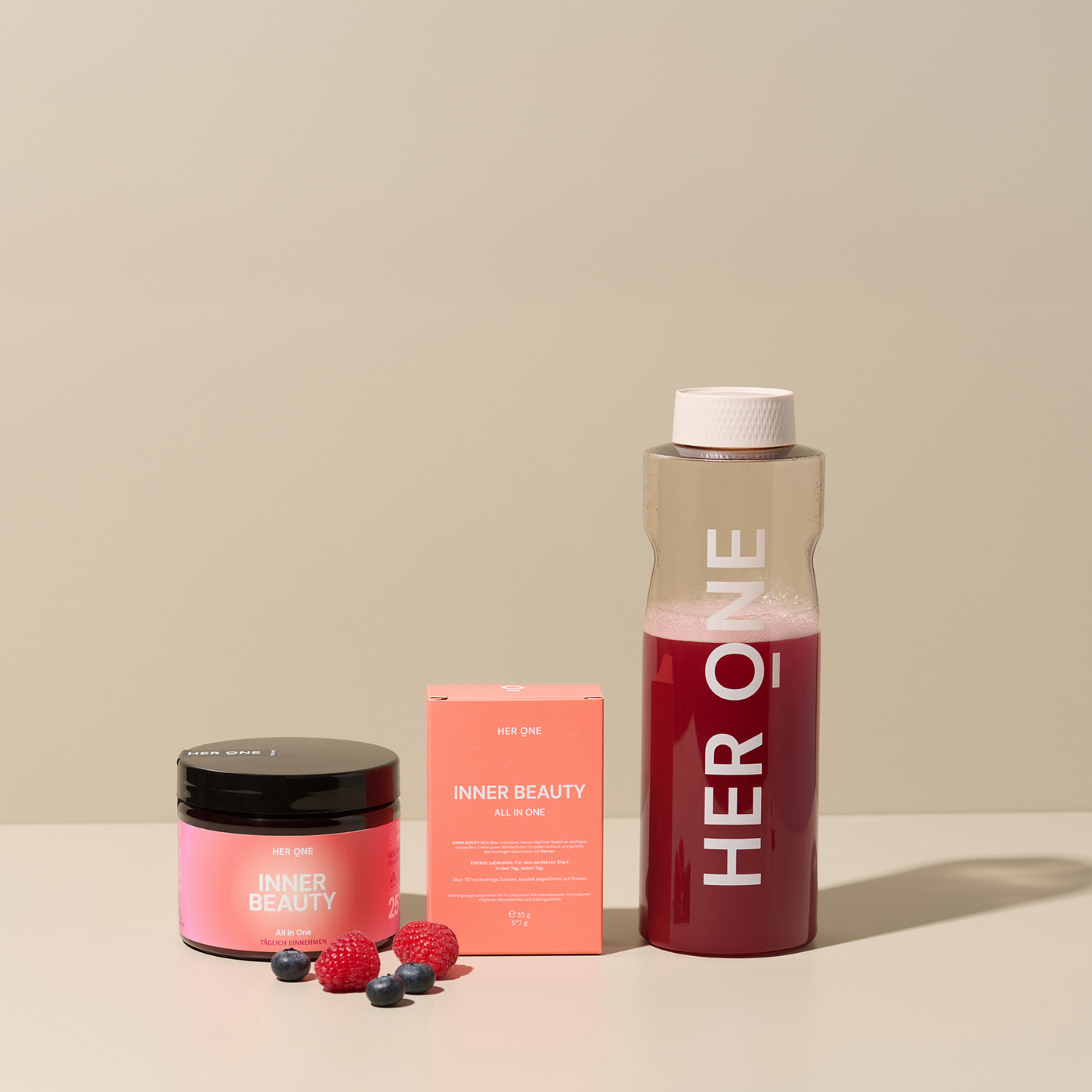 Produits de la marque "HER ONE" avec un verre, une boîte et des fruits sur un fond beige.