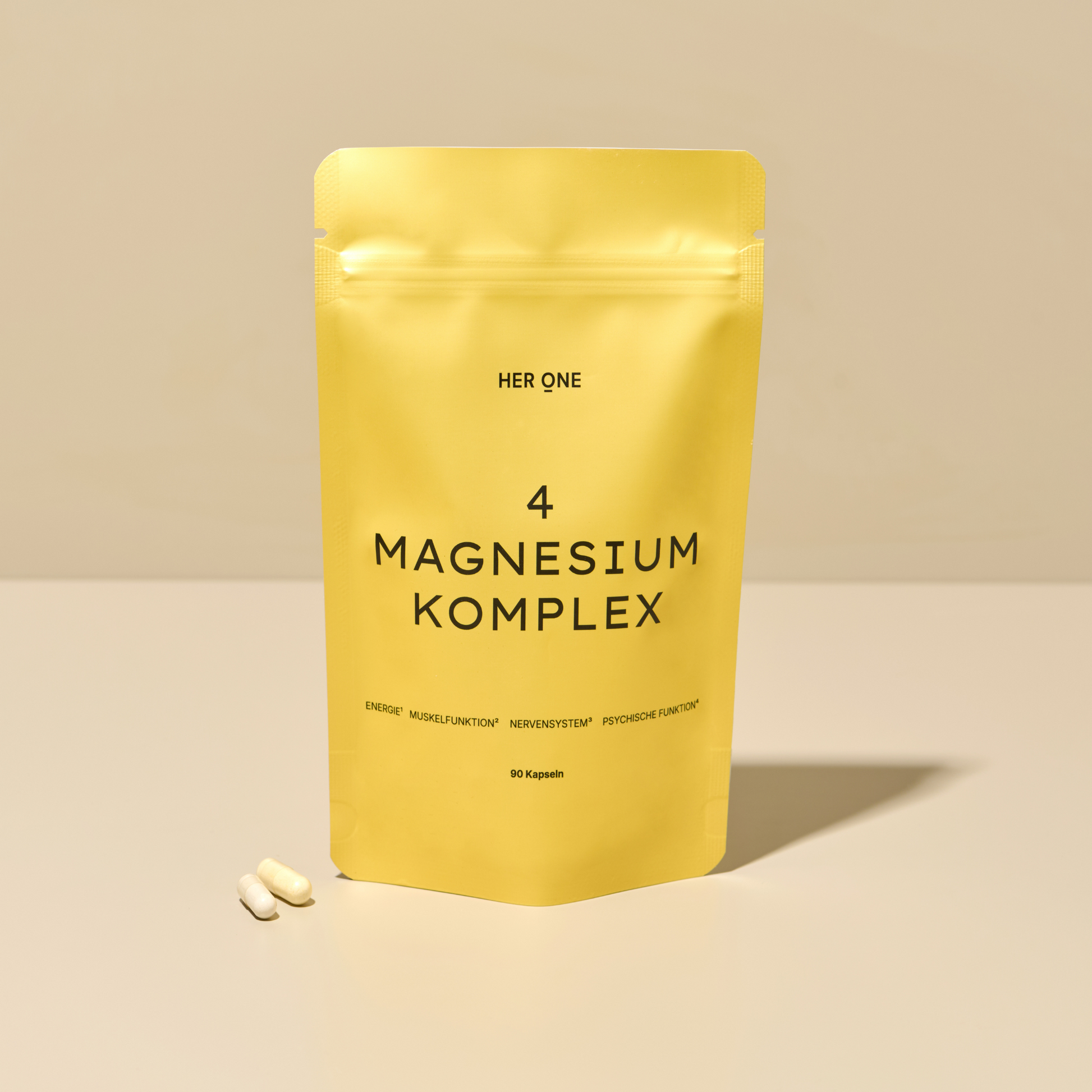 Emballage jaune avec l'inscription "4 Magnesium Complex" et deux capsules blanches à côté sur une surface.