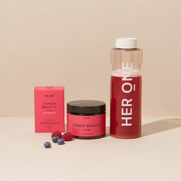 Prodotti a marchio "HER ONE" con bicchiere, scatola e frutta su sfondo beige.