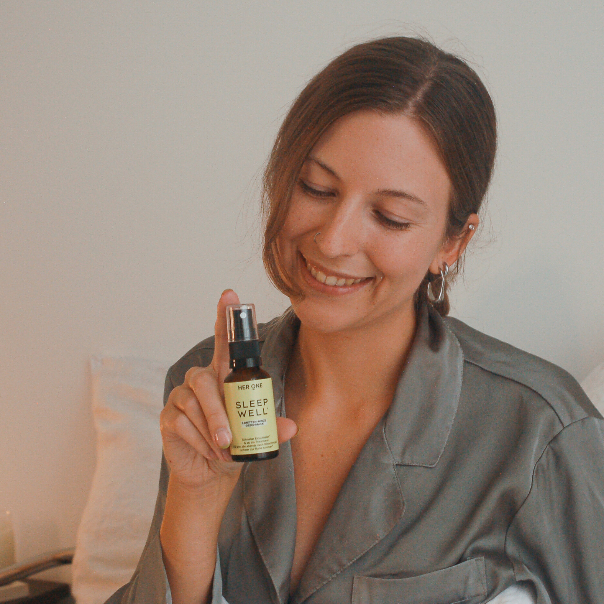 Donna sorridente in pigiama con in mano lo spray SleepWellSpray, routine serale per una buona notte di sonno