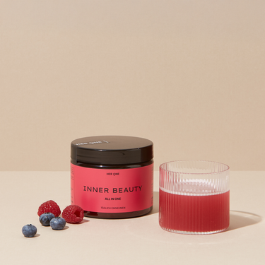 Barattolo rosso scuro HER ONE INNER BEAUTY bacche e succo mescolato in un bicchiere.