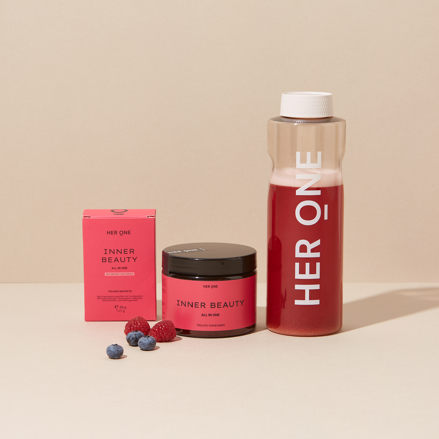 HER ONE" merkproducten met een glas, een doos en fruit op een beige achtergrond.