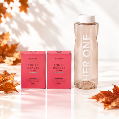 Zwei rosa Schachteln der Marke "Her One Inner Beauty" und eine Wasserflasche, umgeben von Herbstlaub.