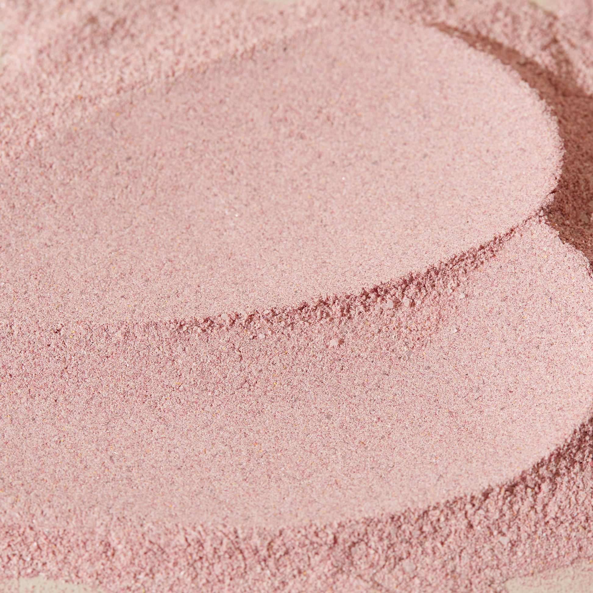 Nahaufnahme von rosa pulverartigem Material mit leicht unebenen Strukturen und Texturen.