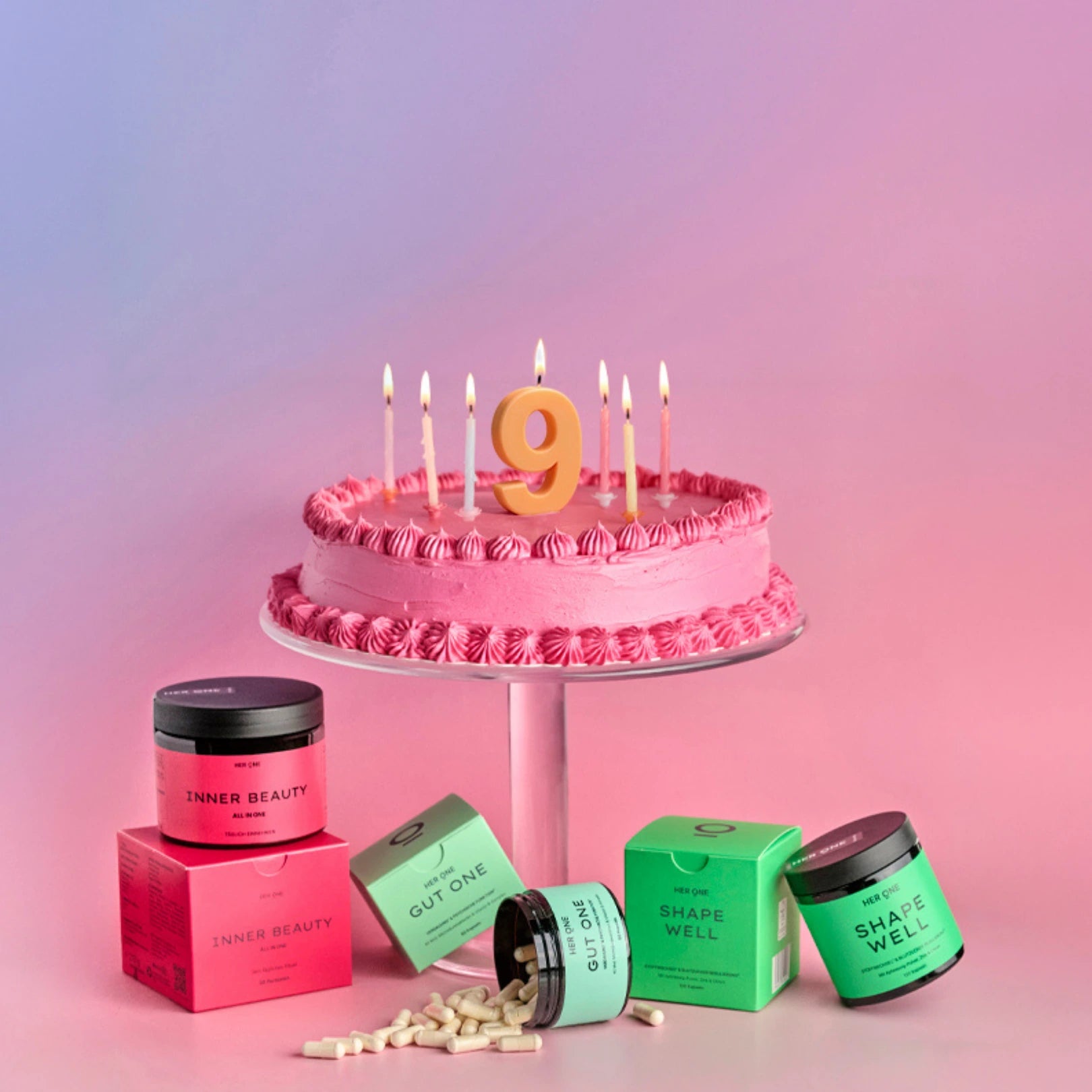 HER ONE products next to a birthday cake on a pink background