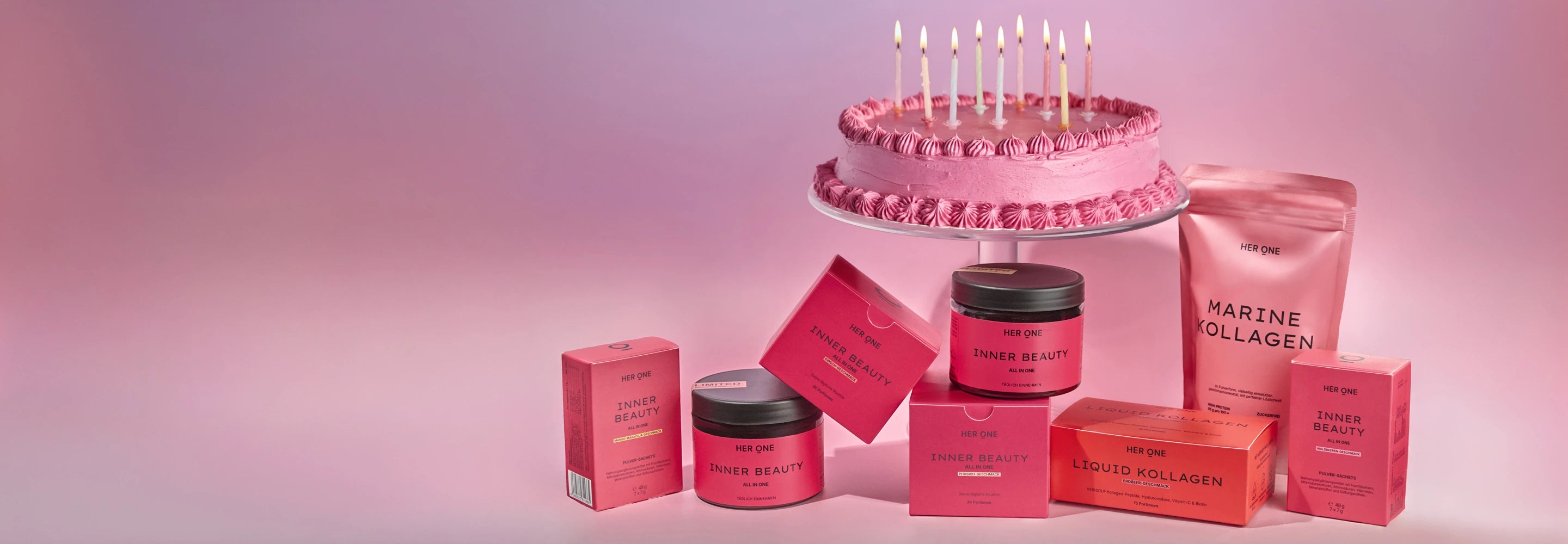 HER ONE Produkte vor einer Geburtstagstorte auf rosa-violettem Hintergrund.