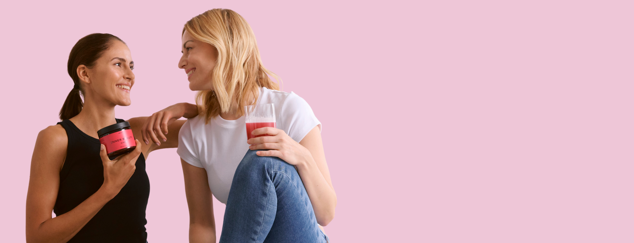 Zwei Frauen lächeln sich an. Die eine Frau. hält eine INNER BEAUTY Dose in der Hand, die andere ein Glas mit INNER BEAUTY.