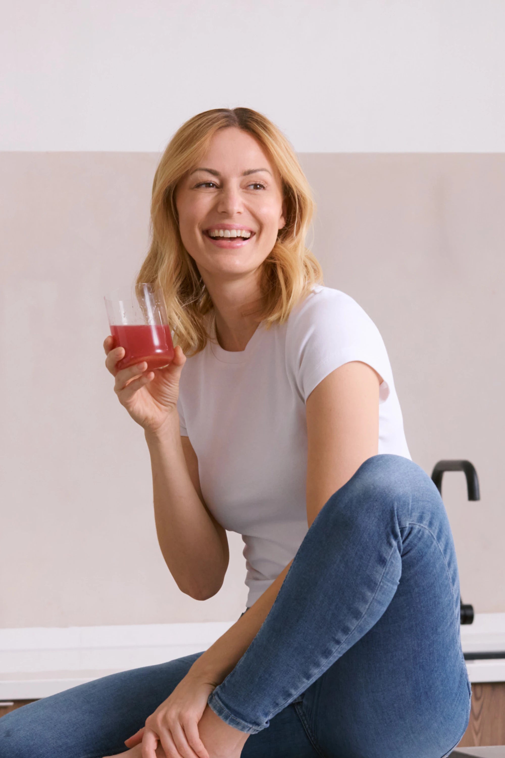 Frau lächelt und hält ein Glas mit INNER BEAUTY in der Hand