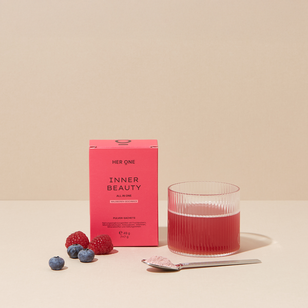 Her One INNER BEAUTY Sachets (Waldbeere) im Hero Shot. Pulver im Glas mit Beeren, Löffel und Pulver.