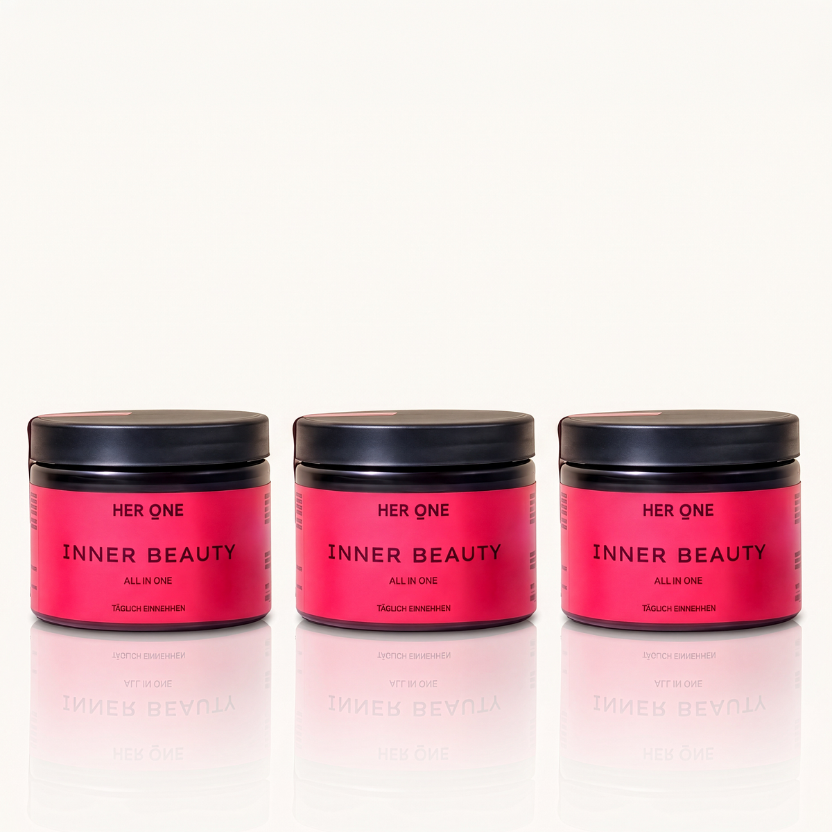 Drei rote Gläser mit dem Aufdruck "Her One Inner Beauty" und schwarzem Deckel nebeneinander auf weißem Hintergrund.