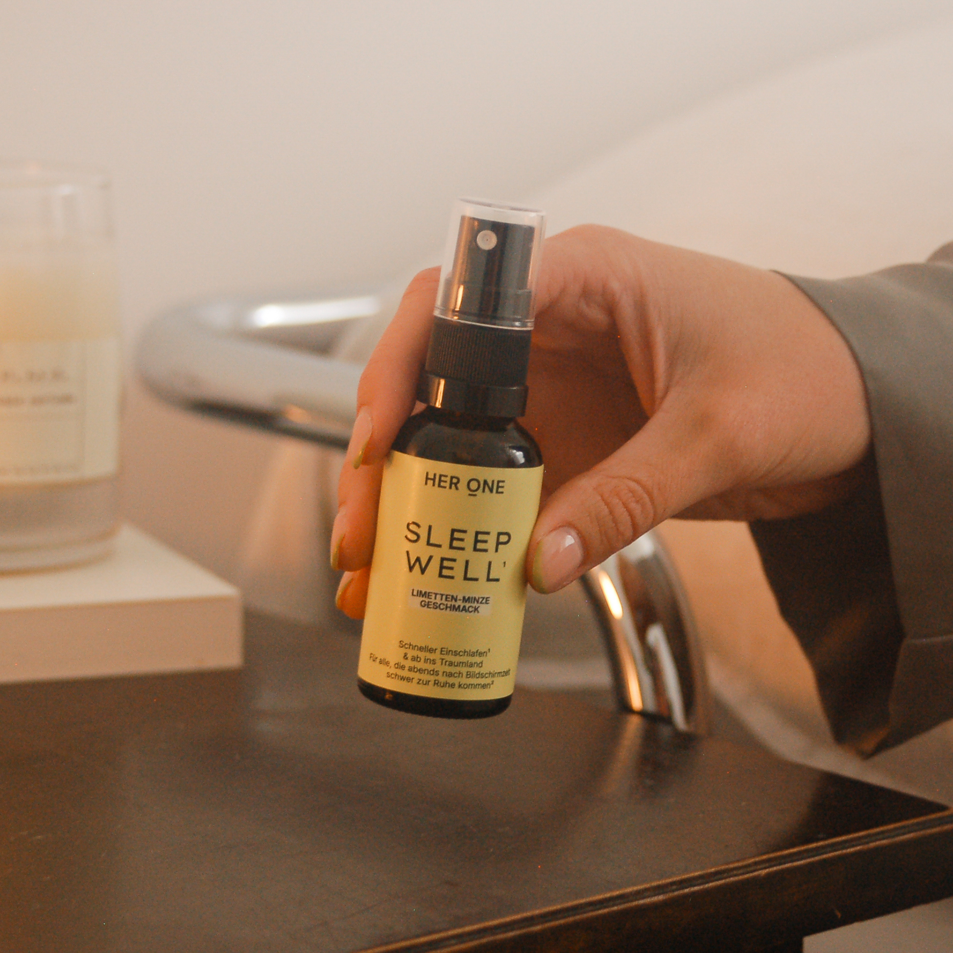 Sleep Well Spray auf Nachttisch neben Kerze, Hand greift zur Flasche, Abendroutine für besseren Schlaf
