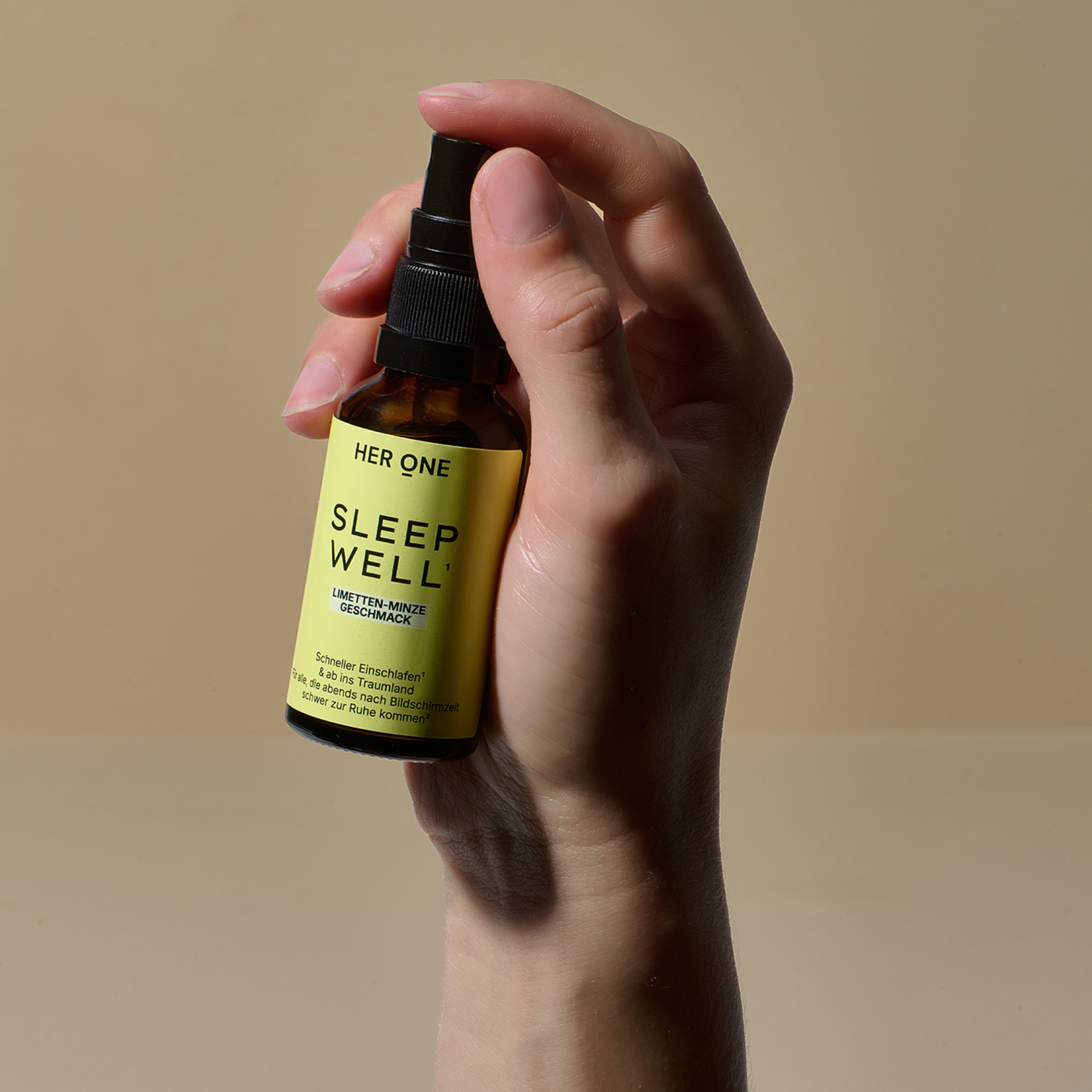 Hand hält Sleep Well Spray von Her One, zeigt Größenverhältnis der Flasche, beige Hintergrund