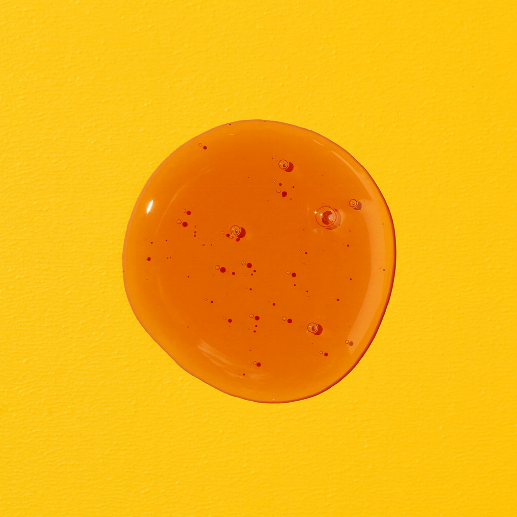 Nahaufnahme von LIQUID BEAUTY Mango-Maracuja-Geschmack Flüssigkeit, glänzend mit kleinen Blasen auf gelbem Hintergrund