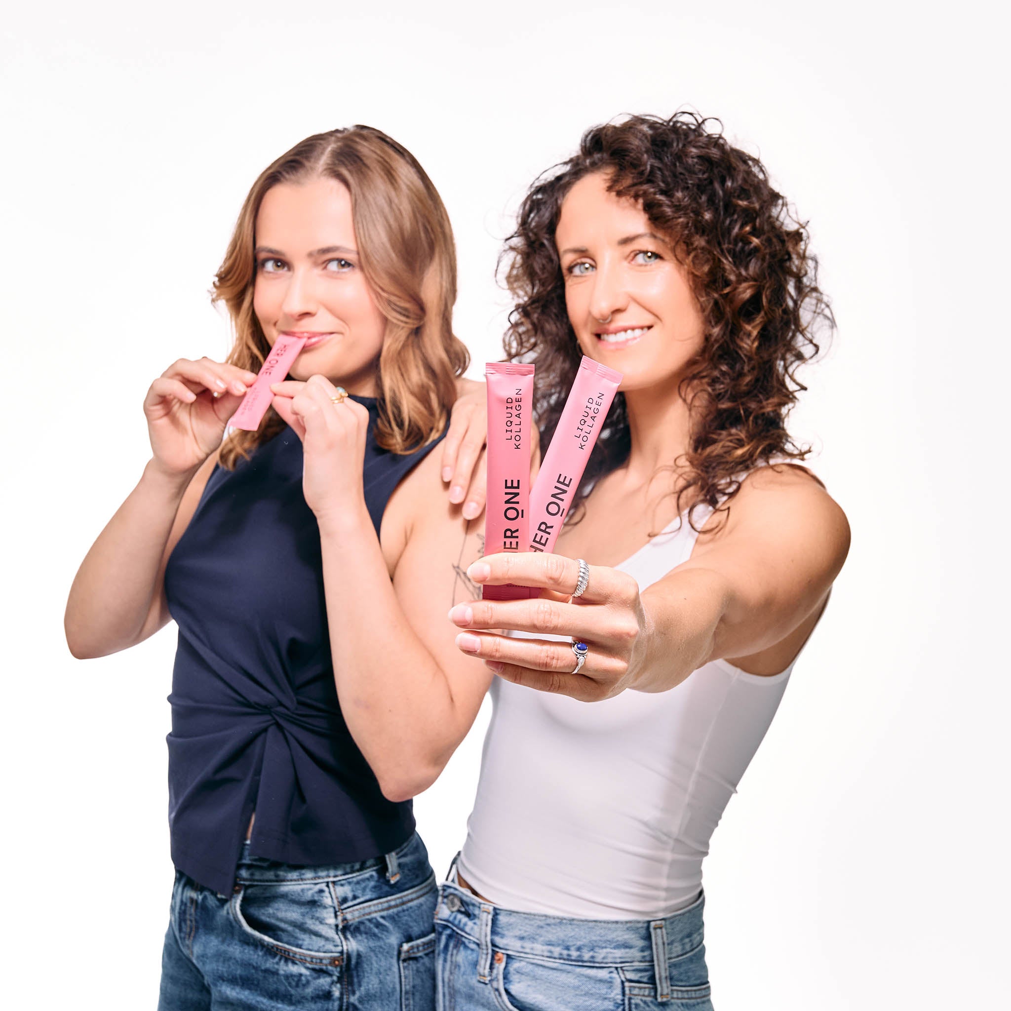 Due donne tengono in mano le bustine di collagene liquido HER ONE