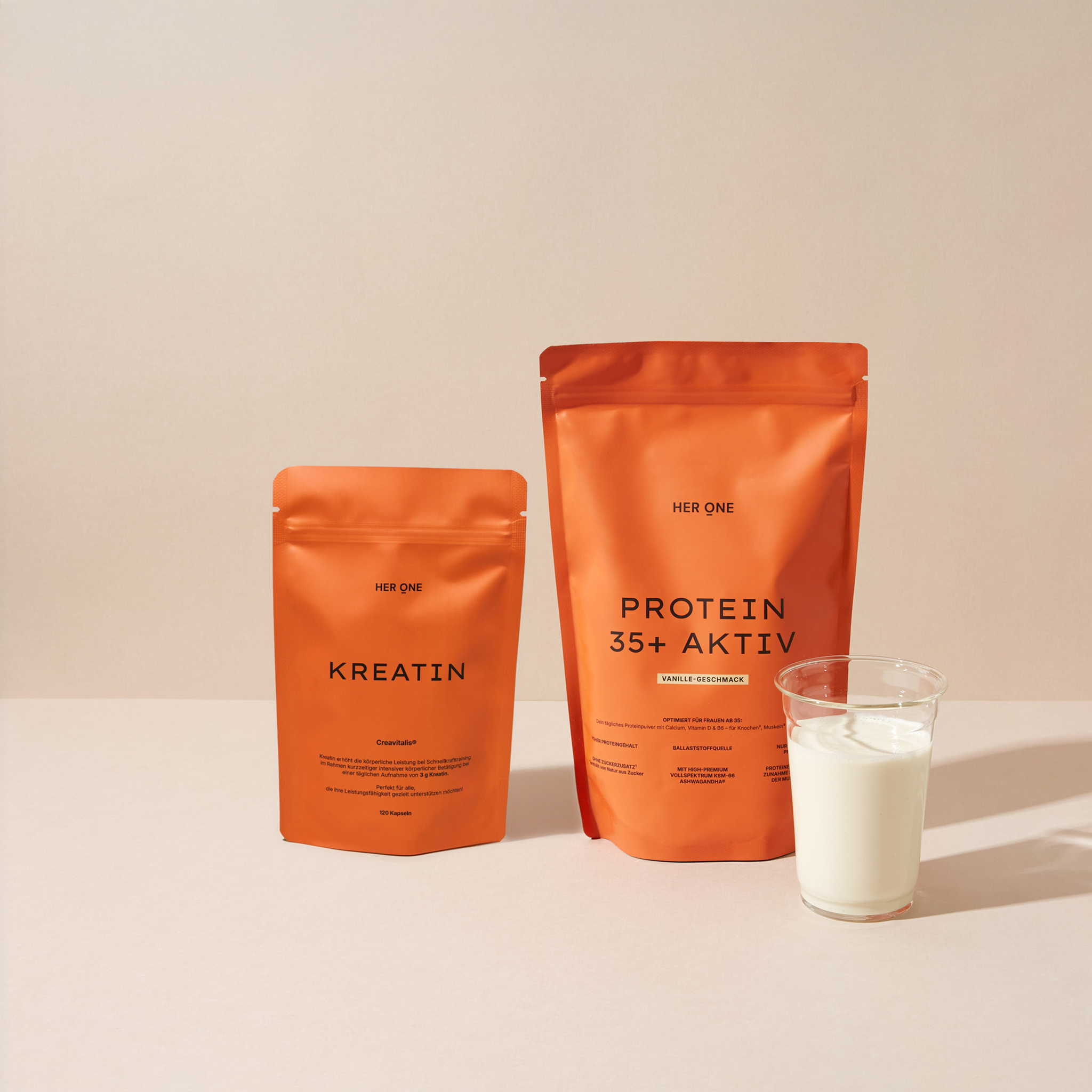 Orange Beutel HER ONE KREATIN und PROTEIN 35+ AKTIV (Vanille) mit einem Glas Milch.