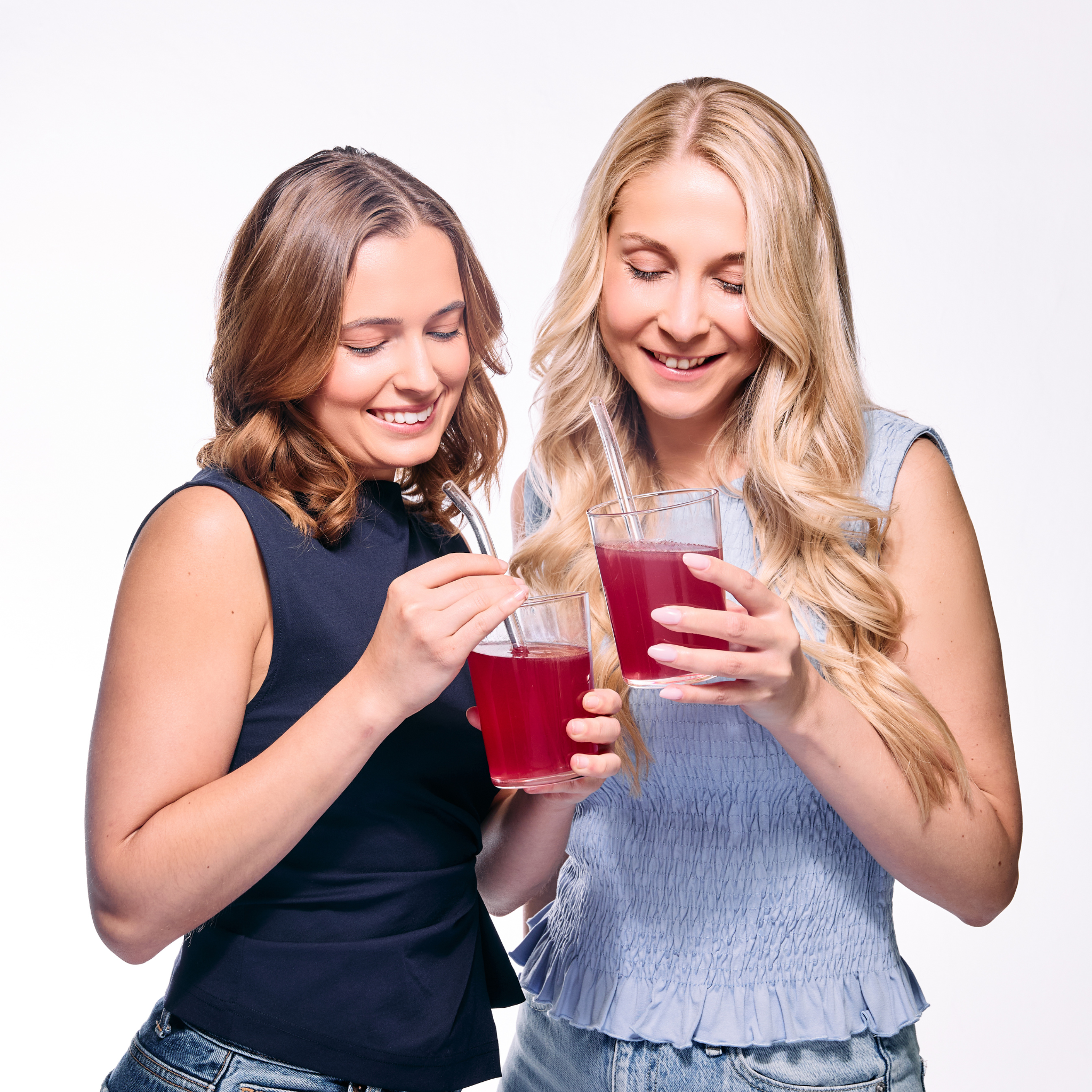 Zwei Frauen trinken NAD+ Skin Glow Himbeergetränk mit Strohhalm