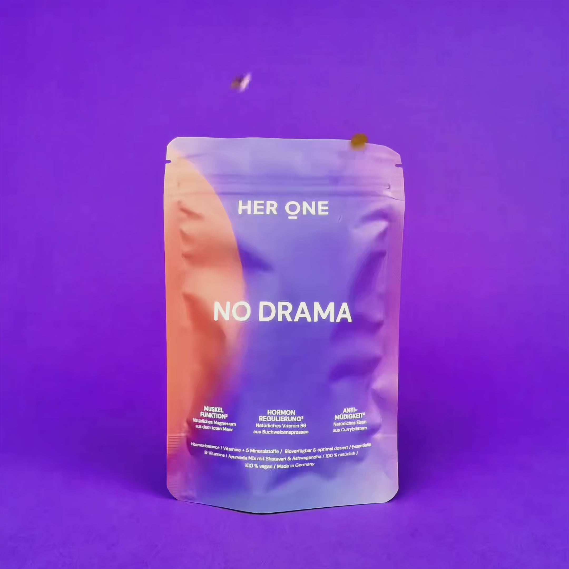 NO DRAMA Packung auf violettem Grund, während buntes Konfetti von oben auf das Produkt herabfällt.