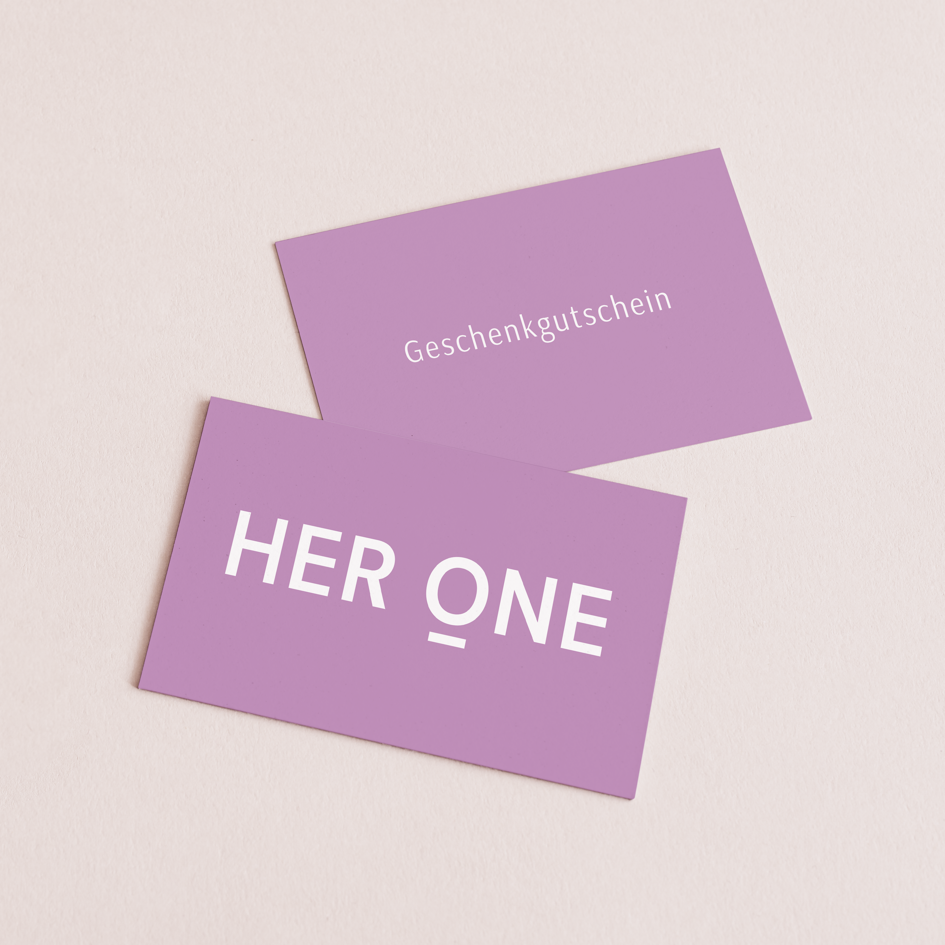Deux chèques-cadeaux violets avec les inscriptions "Chèque-cadeau" et "HER ONE" sur fond clair.