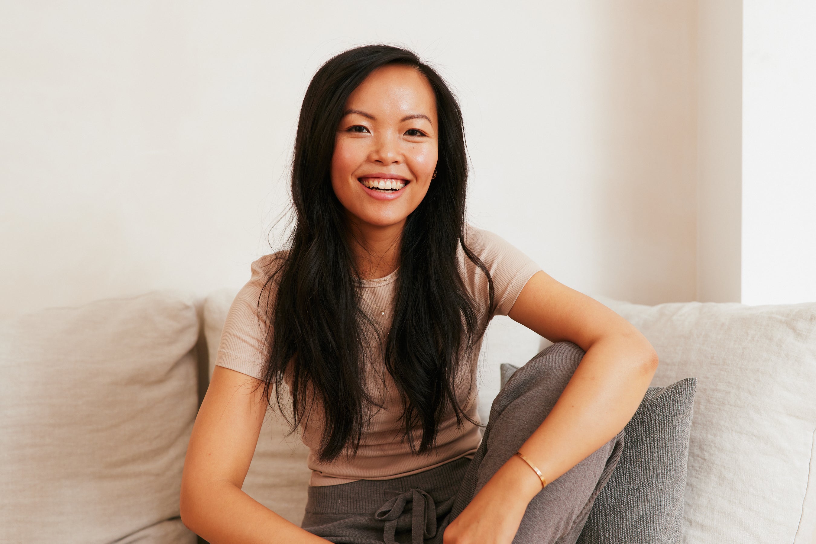 Smiling dream with long hair sits relaxed on a bright sofa.