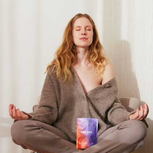 Woman meditates with closed eyes and a product bag on her lap.