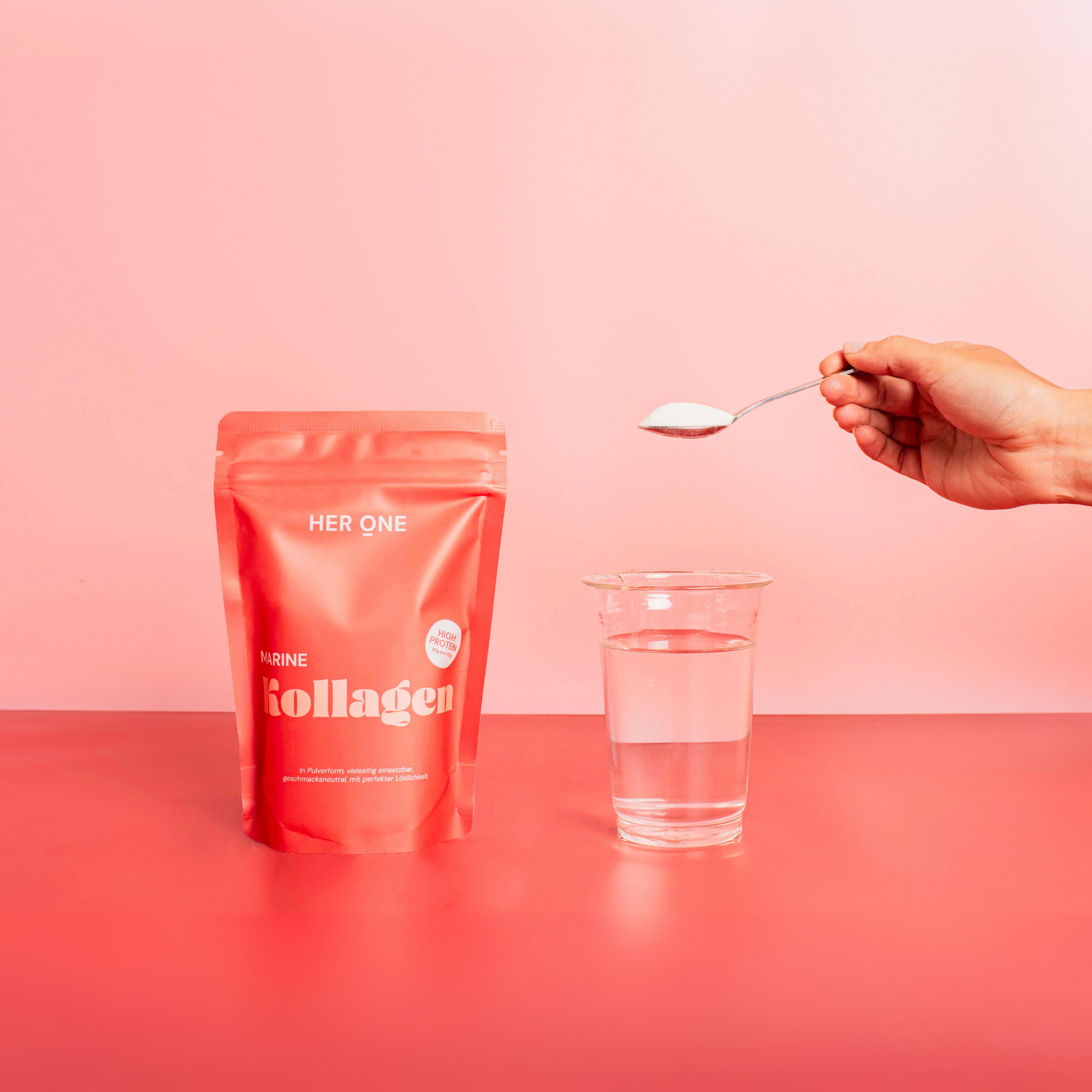 Hand holding spoon with powder over glass of water, next to a pink package labeled "HER ONE Collagen".