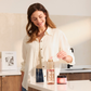 Woman in a white shirt mixes powder in a drinking bottle in a modern kitchen. A glass of powder stands next to it.