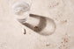 A glass of water and a capsule lie on a light-colored stone surface.