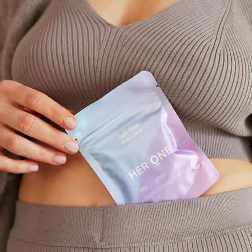 A person puts a pack of "GutOne" food supplements in the waistband of her knitwear.