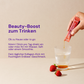 A hand pours liquid from a red stick into a glass next to two strawberries. Text describes a beauty drink.