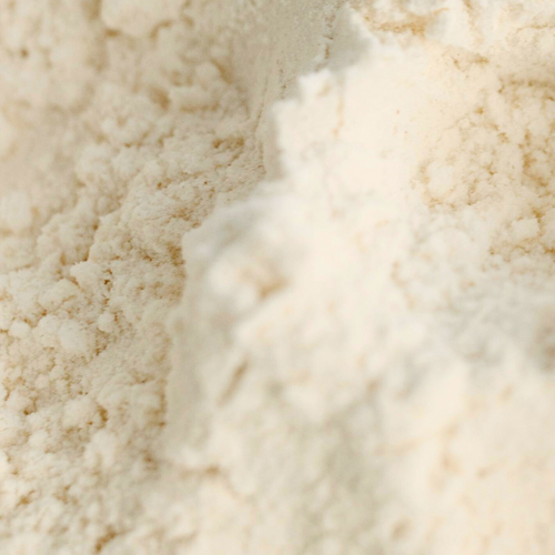Close-up of loose, beige powder, presumably flour, with a slightly uneven surface.