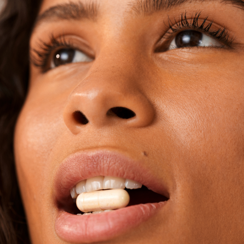 Close-up of a face with two whitish tablets between the lips.