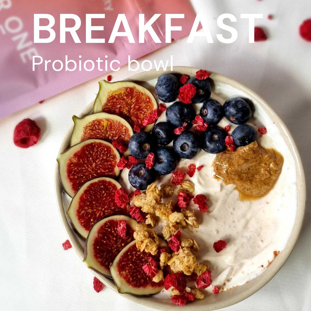 Bowl with yogurt, figs, blueberries, granola and nuts, surrounded by freeze-dried raspberries. text: "BREAKFASTProbioticbowl".