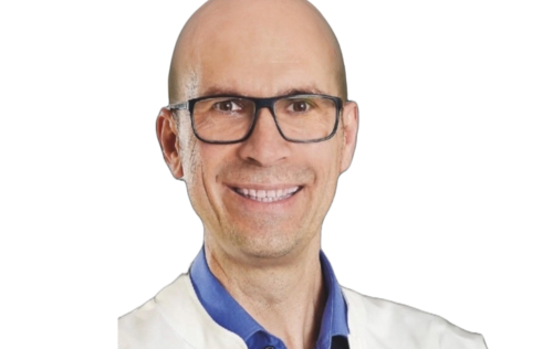 A smiling man with a bald head and glasses, wearing a blue shirt and a white jacket on a white background.