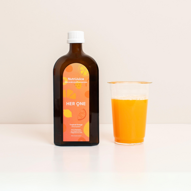 Brown bottle with orange label next to a clear plastic cup with orange juice on a white background.