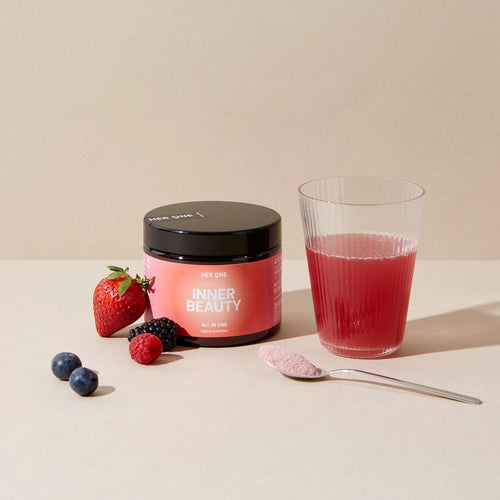 On a table are berries, a glass of red drink, a container labeled "Inner Beauty" and a spoonful of powder.
