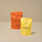 Two bags of food supplements, creatine in orange and magnesium complex in yellow, on a table with capsules.