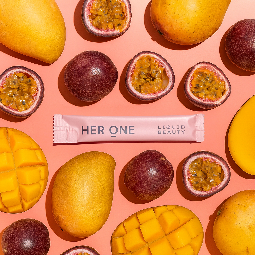 HER ONE Liquid Beauty Stick lies between sliced mangoes and passion fruits on an orange background.