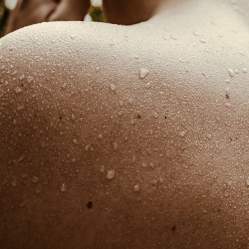 Close-up of a human shoulder with water droplets on the skin, symbolizing freshness and moisture