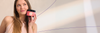 A woman holds a pink container labeled "Inner Beauty" and looks to the side with a smile.
