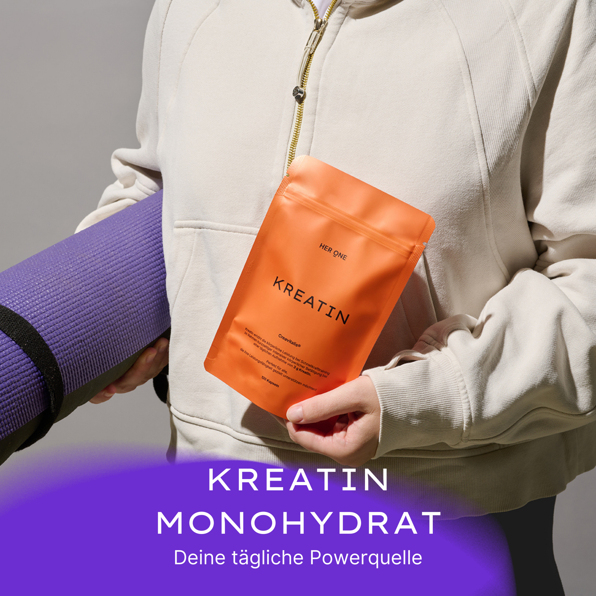 Person in white hoodie holding an orange pack of creatine and a purple yoga mat.