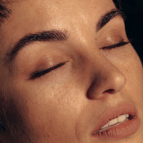 Close-up of a tense face with closed eyes and slightly open mouth.