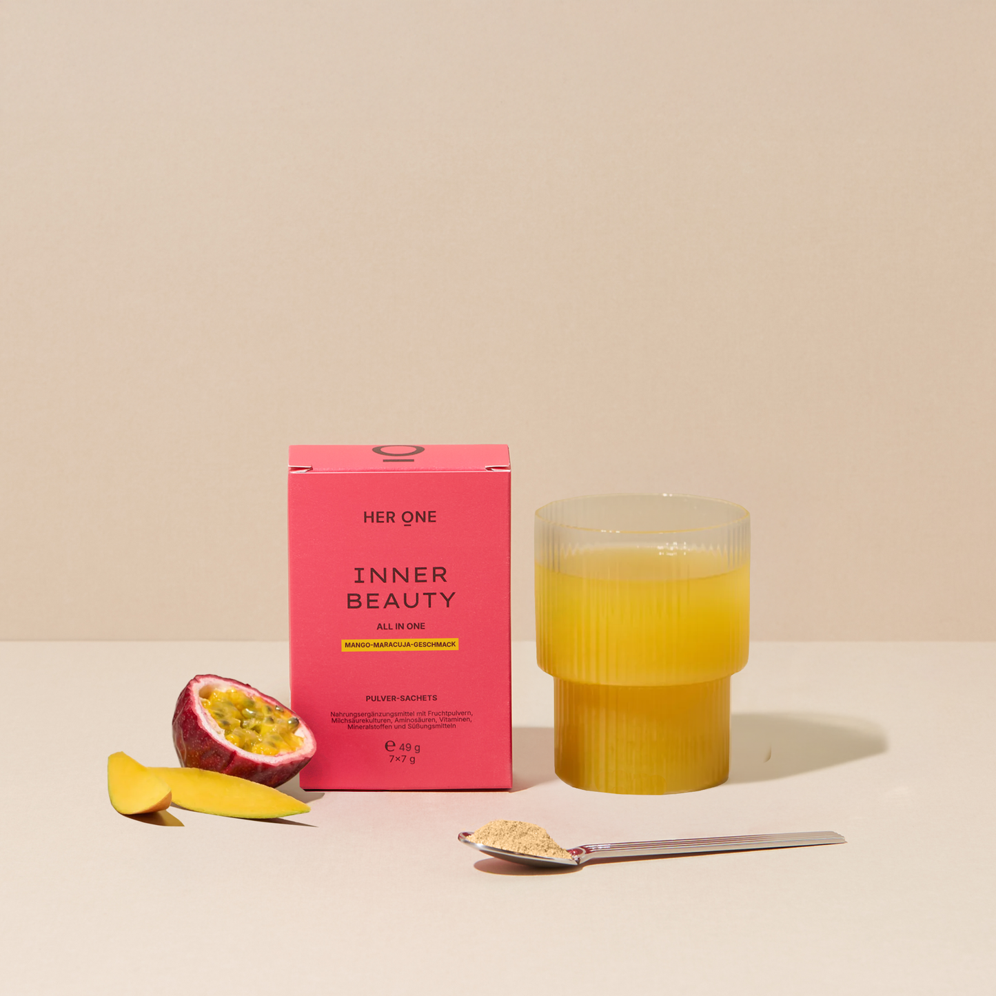 INNER BEAUTY Her One INNER BEAUTY (mangue-fruit de la passion) dans Hero Shot. Poudre dans un verre avec fruit de la passion, mangue et cuillère.