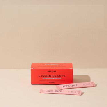 Boîte HER ONE Liquid Beauty Box à la mangue et au fruit de la passion avec deux sticks roses posés dessus, sur fond beige.