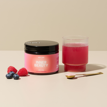 Un verre de boisson rose, une boîte de conserveINNER BEAUTY", des framboises, des myrtilles et une cuillère dorée avec de la poudre.