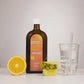 Bouteille brune NutriJuice, orange coupée en deux, morceau d'ananas et un verre d'eau avec de la glace sur fond blanc.